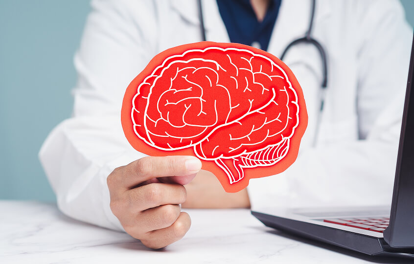 doctor's hand holding an image of a brain